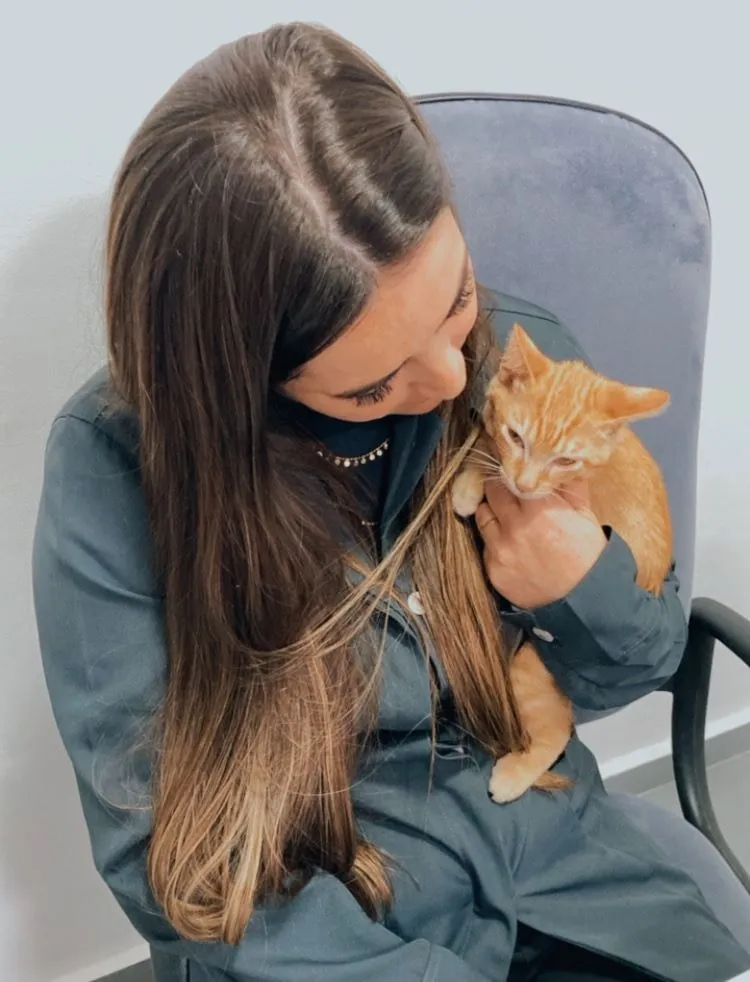 Dra. Clarissa Klein segurando um filhote de gato laranja, fase em que começa a vacinação