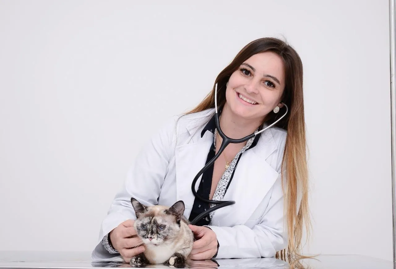 Dra. Clarissa Klein com estetoscópio ao lado de uma gata siamesa